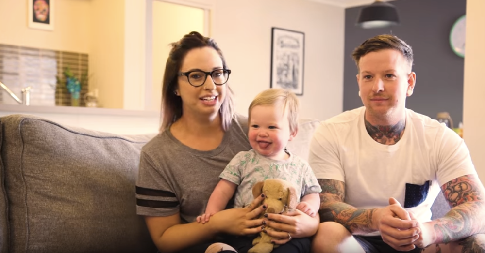 A couple and a baby seating on a couch.